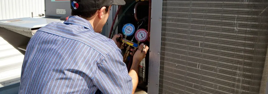 HVAC technician servicing a condenser unit in Cedar Grove